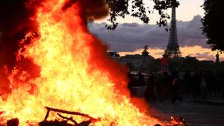 Incêndio é registrado durante protesto contra o alto custo de vida em Paris, com a Torre Eiffel ao fundo; mobilização reuniu estudantes, ex-Coletes Amarelos, agricultores e ativistas de diferentes movimentos.