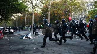 Policiais correm por uma rua enquanto confrontos eclodiam na Praça da República, após uma manifestação não autorizada, no centro de Paris, em 18 de outubro de 2026.
