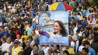 Manifestante exibe faixa com imagem da líder opositora venezuelana María Corina Machado durante ato que cobrou eleições presidenciais e seu retorno ao país, em Caracas, em 22 de outubro de 2026.