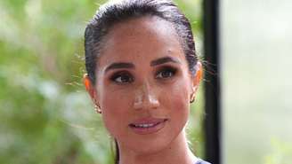 Meghan Markle de cabelo preso e brincos, sorrindo