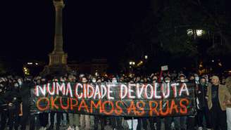 Manifestantes exibem faixa com os dizeres “Em uma cidade abandonada, ocupamos as ruas” durante protesto em Lisboa contra a escassez de moradias e os baixos salários.