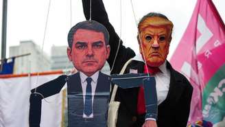 Manifestante usando máscara do presidente norte-americano, Donald Trump, e segurando um boneco de Flávio Bolsonaro participa de ato de encerramento da campanha de Lula, na véspera do segundo turno da eleição presidencial, no sábado (24), em São Paulo.