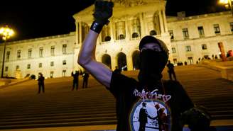 Um manifestante levanta o punho em frente ao prédio do Parlamento durante um protesto organizado por sindicatos portugueses e ativistas pela moradia, enquanto o Parlamento delibera sobre o orçamento de 2027, em Lisboa, em 27 de outubro de 2026