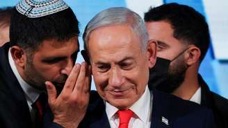 Um assessor conversa com o primeiro-ministro de Israel e líder do Likud, Benjamin Netanyahu, enquanto ele faz uma declaração após a divulgação das pesquisas de boca de urna das eleições legislativas israelenses, na sede do partido em Jerusalém, em 28 de outubro de 2026.