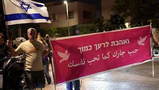 Ativistas com um cartaz que diz 'Ame o seu próximo' instam o opositor Gadi Eisenkot a tentar formar um governo que inclua partidos liderados por árabes