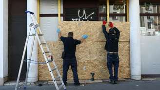 Funcionários protegem com placas de madeira um supermercado Franprix, em Paris, em 30 de outubro de 2026, véspera de novas manifestações nacionais contra o alto custo de vida e a desigualdade.