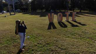 Uma mulher fotografa uma placa de votação do lado de fora de um local de votação no último dia de votação antecipada na Geórgia, antes das eleições de meio de mandato, em Atlanta, no estado da Geórgia, Estados Unidos, em 30 de outubro de 2026.