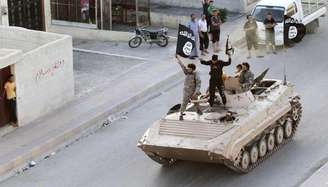 <p>Militantes do Estado Islâmico durante parada militar pelas ruas de Raqqa, no norte da Síria em junho</p>