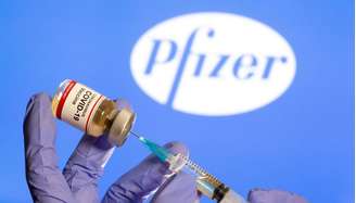 Mulher segura frasco rotulado como de vacina contra Covid-19 em frente ao logo da Pfizer em foto de ilustração
30/10/2020 REUTERS/Dado Ruvic