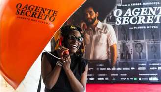 Isabél Zuaa se diverte com o orelhão usado na divulgação de 'O Agente Secreto': uma portuguesa retinta em Hollywood