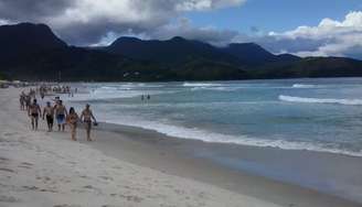 <p>De acordo com a Climatempo, o dia será de céu nublado nesta segunda-feira no litoral paulista; na foto, banhistas caminham por praia de Maresias</p>