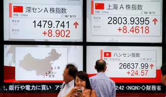 Pessoas caminham em frente a paineis eletrônicos de ações chinesas em Tóquio
11/09/2018
REUTERS/Toru Hanai