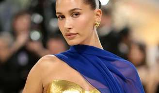 Hailey Bieber surge no Met Gala 2026 com look dourado e azul que rapidamente chama atenção nas redes sociais.