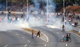 Pessoas reagem ao disparo de gás lacrimogêneo perto de base aérea em Caracas
30/04/2019 REUTERS/Carlos Garcia Rawlins
