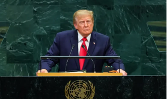 Donald Trump de terno azul marinho, camisa branca e gravata vermelha durante do púlpito da ONU, com o brasão da ONU em tons amarelos