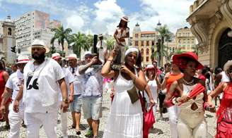 Imagem mostra pessoas em uma celebração religiosa na rua.