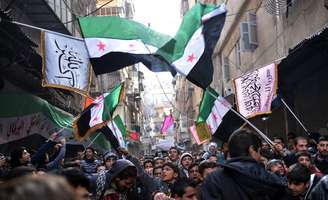 Rebeldes sírios marcham em Aleppo, cidade-berço da revolta contra Assad, com a antiga bandeira síria, símbolo do levante que se tornou guerra civil