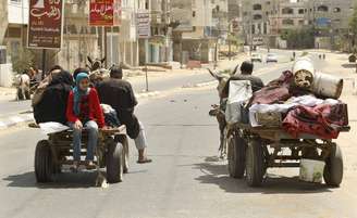 <p>Palestinos, que fugiram de suas casas, adjacentes à fronteira com Israel, andam de carroça e seguem para uma escola das Nações Unidas, no norte da Faixa de Gaza, neste domingo, 13 de julho</p>