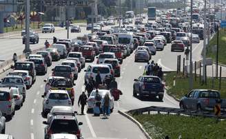 Pessoas atravessam o trânsito ao longo de uma rodovia enquanto taxistas bloqueiam o caminho para o aeroporto internacional de Santiago durante um protesto contra as tecnologias Uber e Cabify em Santiago