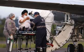 Funcionário do setor de saúde ajuda paciente de Covid-19 em Manaus a embarcar em avião do Exército em direção ao Maranhão. 15/1/2021. REUTERS/Bruno Kelly