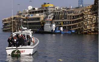 <p>Oficiais da Marinha levam uma coroa de flores ao Costa Concordia para marcar o segundo aniversário da tragédia na ilha de Giglio, em 13 de janeiro de 2014</p>