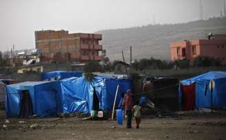 Refugiados sírios na Turquia andam entre barracos de abrigos na fronteira do país