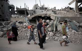 Pessoas carregam poucos pertences que resistiram aos confrontos em Gaza