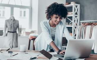 Mulher negra mexendo no computador em uma loja de roupa