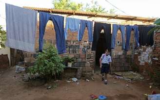 <p>Menina caminha sob as roupas no varal de sua casa em Lambare, próximo a Assunção, nesta imagem de arquivo de 2 de abril de 2014. O nível de pobreza na América Latina se mantém desde 2012</p><p> </p>