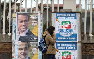 Mulher passa por cartazes de campanha eleitoral em Pomigliano D'Arco, na Itália 21/02/2018 REUTERS/Alessandro Bianchi