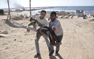 <p>Palestinos carregam o corpo de uma criança morta por um ataque israelense em Gaza, em 16 de julho</p>