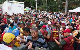 Soldados venezolanos tratan de controlar a la multitud que se aglomeró para intentar comprar pollo en un Mega-Mercal, un mercado estatal subsidiado, en Caracas, 24 de enero de 2015.  Los dueños de una importante cadena de tiendas de Venezuela fueron detenidos por "provocar" una "guerra económica" en el país, anunció el domingo el presidente Nicolás Maduro sin mencionar el nombre del comercio que medios locales identificaron como las farmacias Farmatodo.