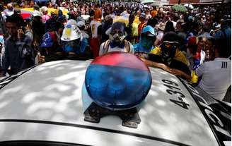 Manifestantes cercam veículo de patrulha durante o protesto contra o governo de Maduro em Caracas