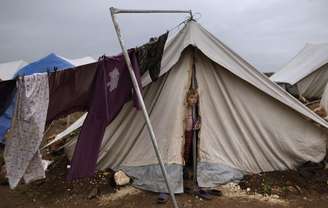 Menina síria cuja família fugiu de Idlib olha para fora de sua barraca, no campo de refugiados de Atmeh, na Síria
