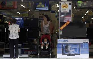 Mulher com criança no colo examina máquina de lavar em uma loja de São Paulo. 18/02/2013.