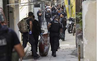Policiais carregam corpo durante operação na favela do Jacarezinho