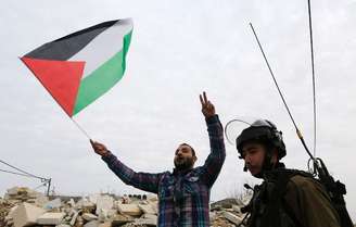 Manifestante palestino discute com soldados israelenses durante protesto contra assentamentos judaicos perto de Ramallah, na Cisjordânia, no início de dezembro
