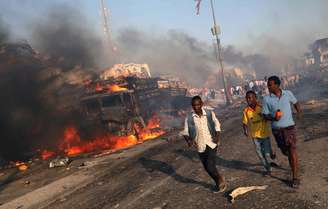 Homens deixam local da explosão na Somália
