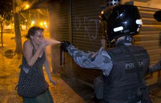 <p>Policial militar joga gás de pimenta no rosto de uma mulher durante o protesto no Rio de Janeiro</p>