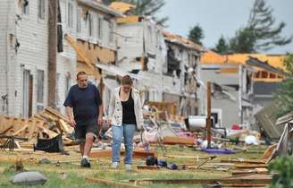 <p>Moradores da província canadense de Ontário caminham em meio a casas destruídas pelo tornado que atingiu a região</p>