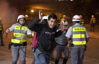 <p>Estudante ergue as mãos enquanto tenta passar por policiais em São Paulo.</p>
