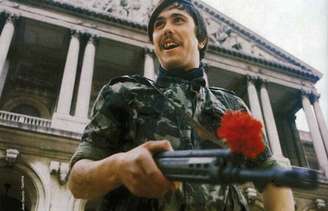 <p>Soldado segura arma "enfeitado" com um cravo, símbolo da Revolução de 1974, em Portugal</p>