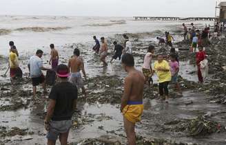 <p>Moradores à beira-mar após a passagem do tufão Rammasun, no litoral da cidade de Rosário, ao sul de Manila</p>