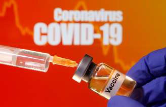 Foto de ilustração mostra frasco com rótulo de vacina em frente a cartaz de Covid-19
10/04/2020 REUTERS/Dado Ruvic/Illustration