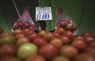 <p>Vendedos ergue sacolas de tomates em feira livre no bairro da Mooca, em São Paulo</p>