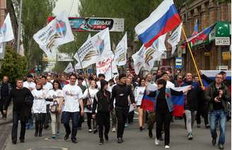 <p>Ucranianos acenam bandeiras russas enquanto pariticpam de marcha dp Primeiro de Maio, na cidade ucraniana de Donetsk, no leste</p>