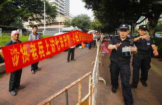 <p>Policiais impedem um jornalista de tirar fotos durante um protesto na frente do prédio do governo em Guangzhou, província de Guangdong, em 16 de junho</p>