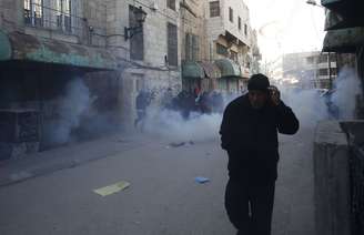 <p>Homens fogem de granadas disparadas por soldados israelenses durante protesto contra a visita do presidente de Israel, Reuven Rivlin, à Cisjordânia ocupada</p>