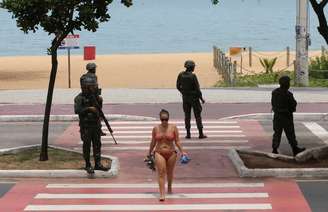 Mulher deixa a praia no litoral de Vitória cuja a segurança é feita por homens do Exército.