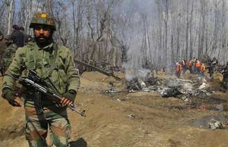 Soldado indiano ao lado de avião militar acidentado na Caxemira, nesta quarta-feira (27)